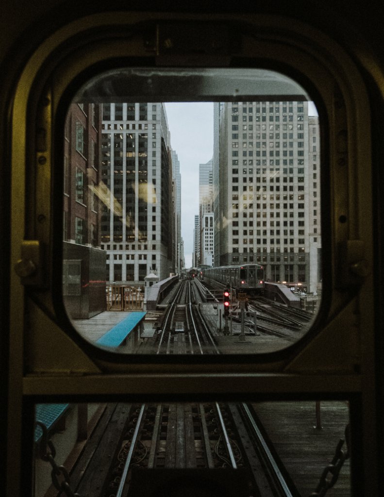 View down a Chicago street canyon from an elevated 'L' train, looking out at the city HBM helps build