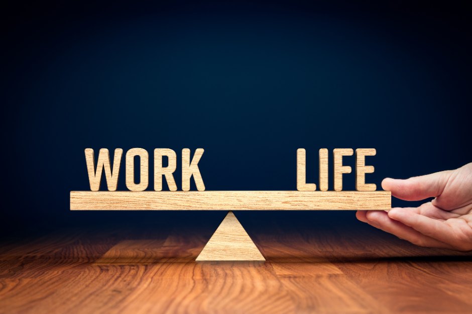 A wooden balance scale weighing the words WORK and LIFE, illustrating work-life balance at HBM
