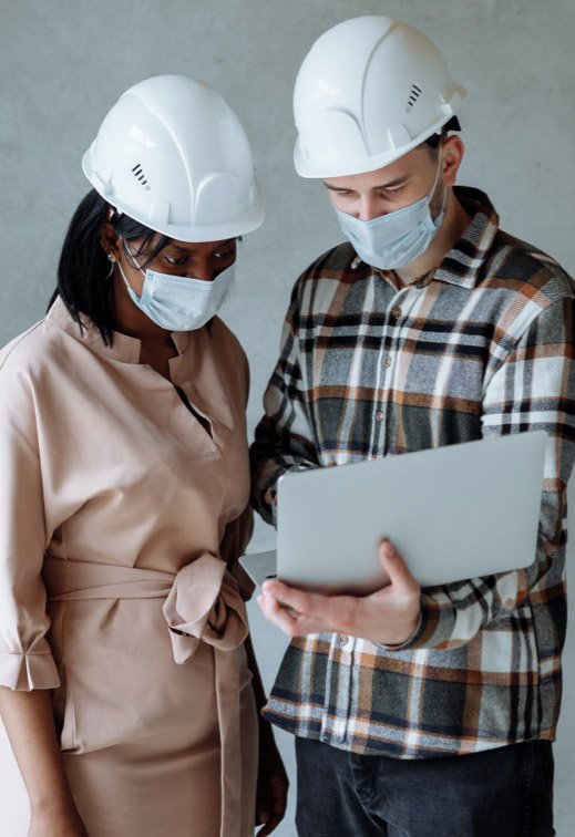 HBM team members reviewing plans on a laptop while wearing protective equipment