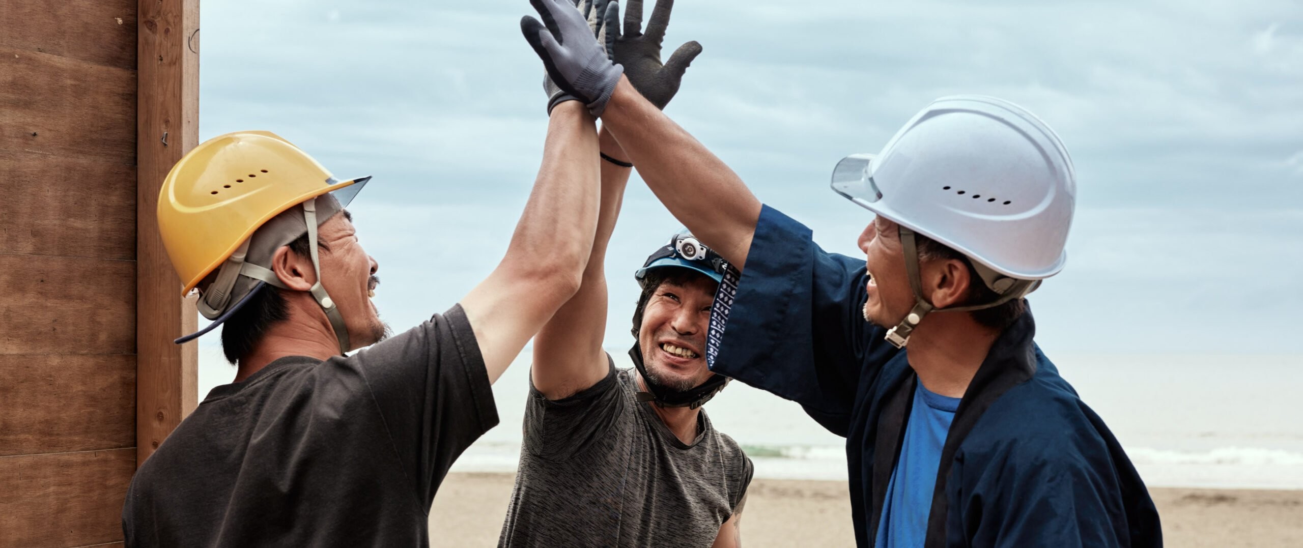 HBM team members in hard hats sharing a high-five on a project site